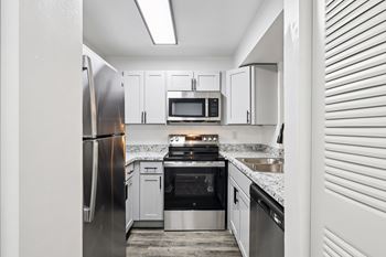 A kitchen with a refrigerator, microwave, oven, and sink.